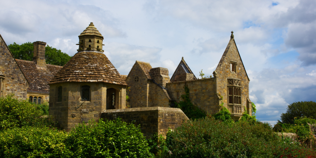 Nymans ruins with bushes in the foreground and a blue sky