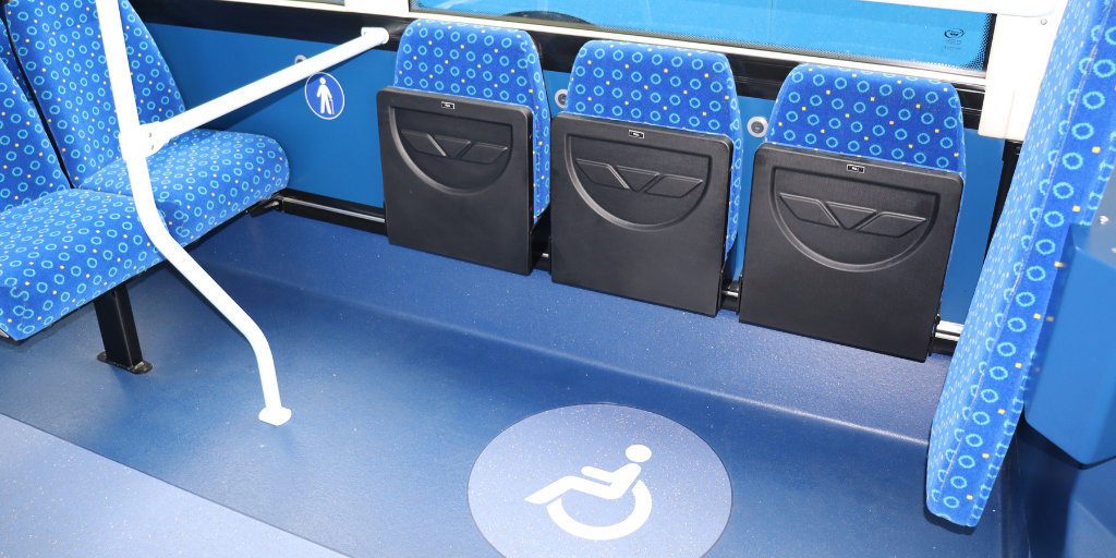 collapsible seats on a bus with a wheelchair logo on the floor to indicate wheelchair space